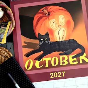 May include: A wall calendar page for October 2027 featuring a black cat lying in front of a large orange pumpkin with a carved face. The word OCTOBER is printed in large yellow letters at the bottom of the illustration, with 2027 below it.