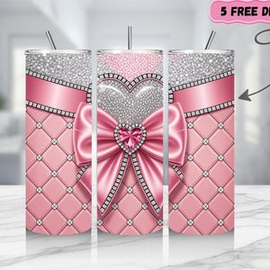 May include: A set of three stainless steel tumblers with a pink quilted pattern, a silver glitter top, and a pink ribbon design. The center tumbler features a large pink bow with a heart-shaped jewel. The text "5 FREE DESIGNS" is in the upper right corner.