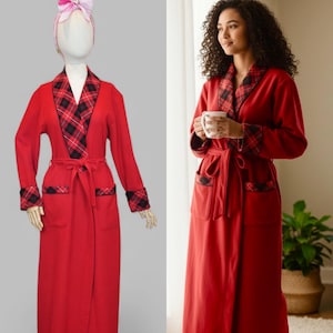 May include: A long, red dressing gown with a plaid collar, cuffs, and pocket details. The gown has a matching belt and is shown on a mannequin and worn by a person. The robe is made of a soft material and is suitable for relaxing.