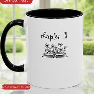 May include: White ceramic mug with a black interior and handle, featuring the text "chapter 18" in black script. Below the text is a black and white illustration of an open book with flowers.