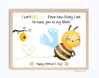 Può includere: Una stampa incorniciata con un'illustrazione ad acquerello di un'ape dei cartoni animati, un alveare e impronte di bambino. Il testo recita: "I can't BEE lieve how lucky I am to have you as my Mom! Happy Mother's Day!"