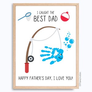 May include: A framed print with a fishing theme, featuring a blue handprint fish and the text "I Caught the Best Dad." Includes a fishing rod illustration, bubbles, and the message "Happy Father's Day, I Love You!"
