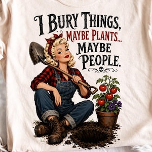 Puede incluir: Camiseta color crema con una ilustración vintage de una mujer con overoles sosteniendo una pala. El texto dice "I Bury Things, Maybe Plants... Maybe People." También se representa una planta de tomate y una calavera.