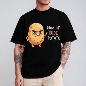 May include: Black t-shirt featuring a cartoon potato with an angry expression. The potato has arms and legs and the text "kind of RUDE POTATO" is printed on the right side of the shirt. The shirt is made of a soft material.