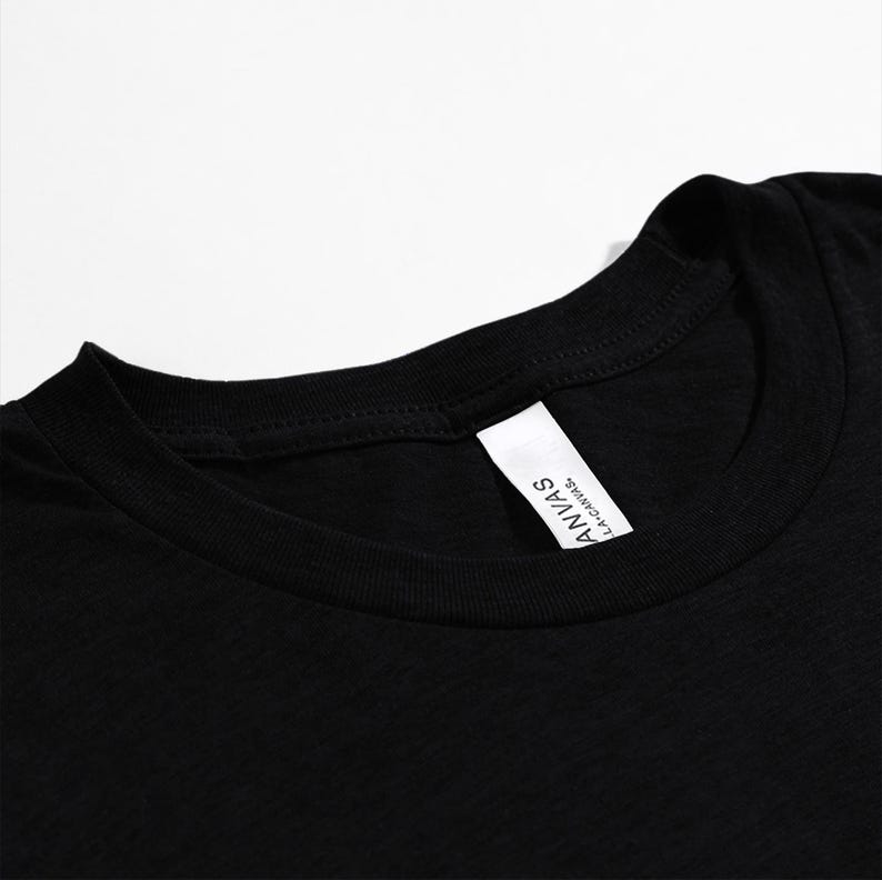 May include: Close-up of a black crew neck t-shirt. The shirt has a white tag on the inside collar with the text "ANVAS L.A. CANVAS."