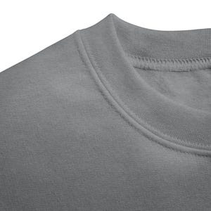 May include: Close-up of a grey crew neck sweatshirt. The collar and shoulder area are visible, showcasing the fabric's texture and stitching details. The sweatshirt is a solid, neutral colour, suitable for various outfits.