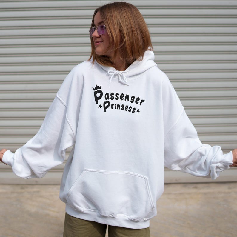 May include: White hoodie with the text "Passenger Prinssess" in black script. The sweatshirt has a front pocket and a drawstring hood. The image shows a person wearing the hoodie.