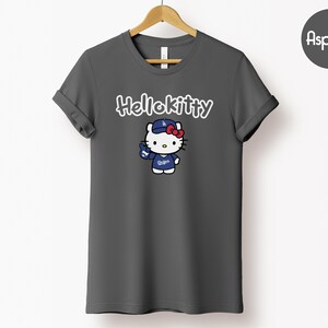 May include: Dark grey t-shirt with a Hello Kitty graphic. The graphic depicts Hello Kitty in a baseball cap and uniform with the text "Dodgers". The words "Hello Kitty" are written above the graphic in white script.