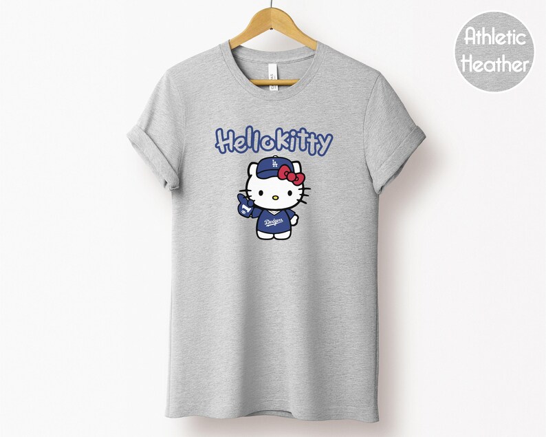 May include: Grey athletic t-shirt with a Hello Kitty graphic wearing a baseball uniform. The text "HelloKitty" is above the graphic. The graphic includes a blue baseball cap and uniform with the word "Dodgers".