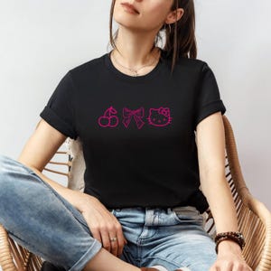 Pu&ograve; includere: T-shirt nera con grafica rosa a ciliegia, fiocco e Hello Kitty. La maglietta a maniche corte &egrave; realizzata in materiale morbido. Il disegno &egrave; centrato sul petto. Un capo d'abbigliamento casual.