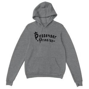 May include: A grey hooded sweatshirt with a front pocket and a drawstring. The black text "Passenger Prinssss" is printed on the front, with a crown above the word "Passenger" and stars on either side of "Prinssss".
