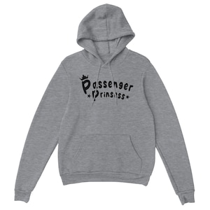 May include: A grey hoodie with a front pocket and a drawstring hood. The sweatshirt displays the text "Passenger Princess" in black, with a crown above "Passenger" and stars either side of "Princess".