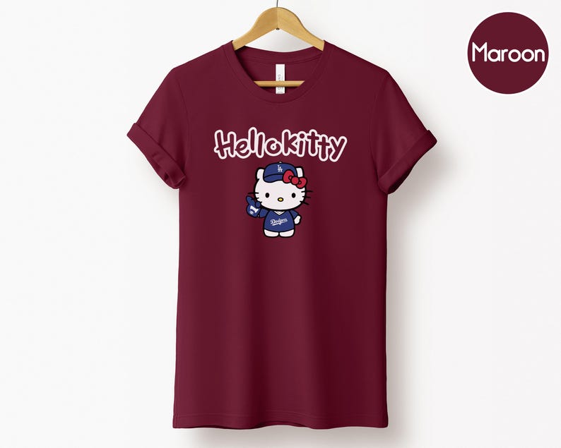 May include: Maroon t-shirt with a Hello Kitty graphic. The graphic depicts Hello Kitty in a baseball cap and uniform. The text "Hello Kitty" is above the graphic in cursive. The word "Maroon" is in a circle in the top right corner.
