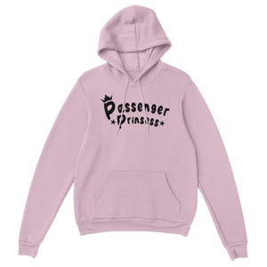 May include: A pale pink hoodie with a hood and a front pocket. The black text on the front says "Passenger Princess" with a crown and stars. The hoodie is made of a soft material.