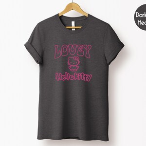 Op de afbeelding: Donkergrijs gem&ecirc;leerd T-shirt met de tekst "LOUEY Hellokitty" in roze. Het ontwerp bevat een afbeelding van Hello Kitty. Het T-shirt hangt aan een houten hanger tegen een witte achtergrond.