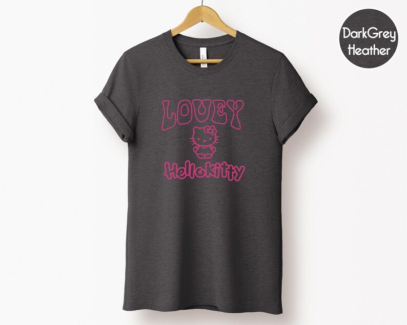 Op de afbeelding: Donkergrijs gem&ecirc;leerd T-shirt met de tekst "LOUEY Hellokitty" in roze. Het ontwerp bevat een afbeelding van Hello Kitty. Het T-shirt hangt aan een houten hanger tegen een witte achtergrond.