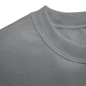 May include: Close-up of a gray sweatshirt. The image focuses on the neckline and shoulder area, showcasing the fabric's texture and stitching details. The sweatshirt appears to be made of a soft, comfortable material.