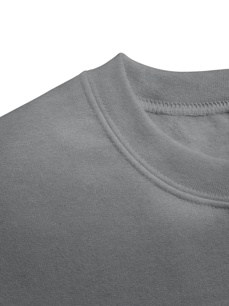 May include: Close-up of a gray sweatshirt. The image focuses on the neckline and shoulder area, showcasing the fabric's texture and stitching details. The sweatshirt appears to be made of a soft, comfortable material.