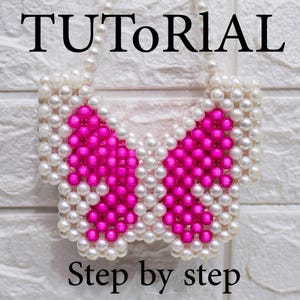 Può includere: Un accessorio a forma di farfalla fatto di perline bianche e rosa. La parola "TUTORIAL" è in alto e "Step by step" in basso. L'accessorio è probabilmente fatto a mano e potrebbe essere una collana o un oggetto decorativo.
