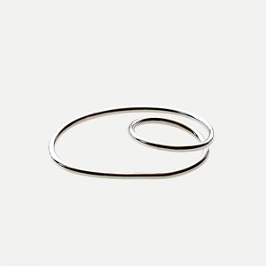 Puede incluir: Un anillo de plata con un diseño ovalado simple y continuo. El anillo está hecho de dos óvalos superpuestos, creando un aspecto único y moderno.