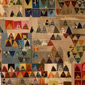 May include: A colorful patchwork quilt with a geometric pattern of triangles. The quilt is made of various fabrics in shades of blue, green, red, yellow, and brown. The triangles are arranged in a repeating pattern, creating a visually interesting and dynamic design.
