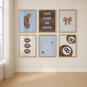 May include: Six framed art prints with gold frames. The prints feature a leopard, leopard print text that reads "YOU LOOK SO GOOD", a bow, three lip prints, text that reads "Guest Check, YOU ARE EXACTLY WHERE YOU NEED TO BE", and two 8-ball prints.
