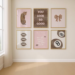 May include: Six framed art prints with gold frames. The prints feature a leopard, text that reads "YOU LOOK SO GOOD", a bow, leopard print lips, text that reads "Past Check, YOU ARE EXACTLY WHERE YOU NEED TO BE", and two 8-ball designs.