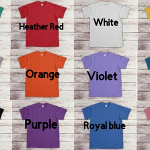 以下が含まれることがあります： 12色のTシャツのコレクション。色は、ジェイド、白、ヘザーレッド、イエロー、ヘザーグレー、オレンジ、バイオレット、ティール、ブラック、パープル、ロイヤルブルー、ピンク。各Tシャツは異なる色で、色はTシャツの前面に黒で印刷されています。