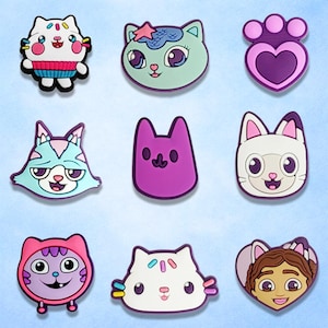 May include: Nine colorful cat-themed charms in various designs. The charms feature different cat faces with unique expressions and colors, including pink, blue, purple, and white. Some charms have additional decorative elements like sprinkles or a heart shape.