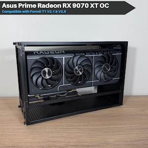 May include: A black computer case with an Asus Prime Radeon RX 9070 XT OC graphics card installed. The graphics card has three black fans and the word "RADEON" is visible. The case is compatible with FormD T1 V2.1 & V2.5.