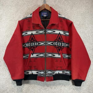 May include: A red Pendleton jacket featuring a geometric pattern in black, white, and grey. This long-sleeve jacket has a full-length front zipper, a fold-down collar, two side pockets, and black ribbed knit cuffs and hem. The interior is lined.