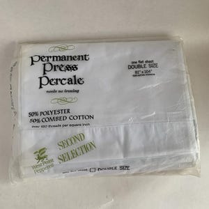 Puede incluir: Una sábana plana blanca de tamaño doble en un paquete de plástico transparente. La sábana está hecha de 50% poliéster y 50% algodón peinado. El texto en el empaque dice "Permanent Press Percale" y "needs no ironing". La sábana mide 206 cm x 264 cm.