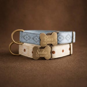 Puede incluir: Dos collares para mascotas con placas de latón en forma de hueso. El superior es azul claro con un patrón geométrico gris y el nombre Bear con 788-874-094. El inferior es crema con estampado de margaritas y el nombre Sadie con 153-254-561.