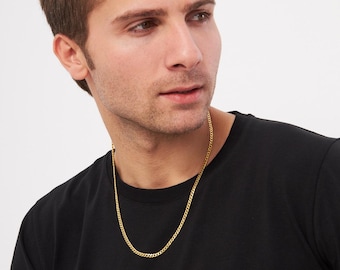 Könnte beinhalten: Eine goldfarbene Kette mit einem Curb-Link-Design. Die Halskette wird über einem schwarzen T-Shirt getragen. Die Kette ist etwa 50 cm lang.