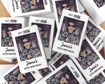 Könnte beinhalten: Eine Ansammlung weißer Schachteln mit einem Foto im Polaroid-Stil einer Person mit Sonnenbrille und herausgestreckter Zunge. Auf den Schachteln steht "EST. 1986" und "Jessie's 40TH BIRTHDAY".
