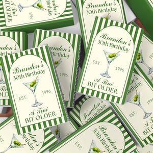 May include: A white ceramic mug with a black handle and the text "But First, Coffee" in a black, bold font. The mug is sitting on a wooden surface.