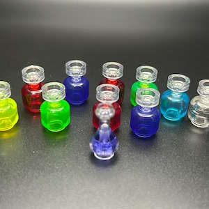 May include: A collection of small, colorful glass bottles with clear stoppers. The bottles contain liquids in various colors, including red, green, blue, and yellow. The bottles are arranged on a dark surface.