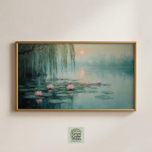 Puede incluir: Pintura de paisaje enmarcada que representa una escena de lago serena con nenúfares rosas, hojas de nenúfar verdes y un sauce llorón. La obra de arte tiene un marco dorado y una paleta de colores pastel con una puesta de sol en el fondo.