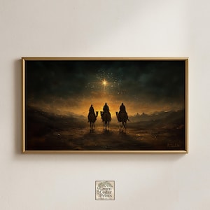 May include: A framed print showing three figures on camels, set against a dramatic sunset and a bright star. The artwork uses a warm palette of golds, browns, and blues, with a gold frame. The print is from Green Cedar Prints.