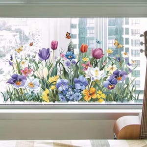 以下が含まれることがあります： チューリップ、パンジー、蝶々が描かれた、鮮やかな花の窓用ステッカー。ステッカーは窓に貼られており、背景には街並みが見えます。花は満開です。