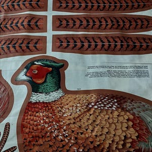 May include: A fabric panel featuring a printed pheasant with a red face, green neck, and brown patterned body, accompanied by separate long tail feathers and printed instructions. The text notes the bird measures 12 inches high and 18 inches long.