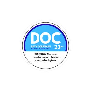 May include: A round sticker with a blue and white design. The word "DOC" is in large white letters on a blue background. Below, it reads "NAVY CORPSMAN 127 YEARS OF EXCELLENCE 23 MOH's". The bottom text says "WARNING: This rate contains respect. Respect is earned not given."