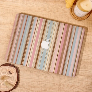 May include: A laptop with a colorful striped design in shades of pink, blue, and brown. The Apple logo is visible on the laptop's surface. The laptop is on a wooden surface.