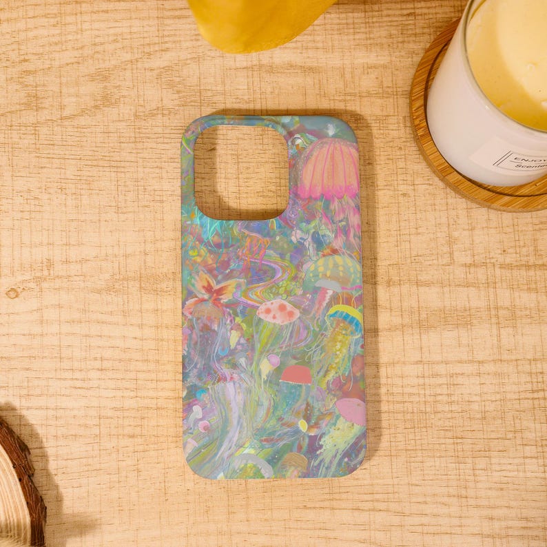 May include: A phone case featuring a vibrant, colorful design of jellyfish and other sea life. The case has a light blue background with pink, yellow, and green accents. The design is artistic and whimsical, perfect for adding a unique touch to your phone.