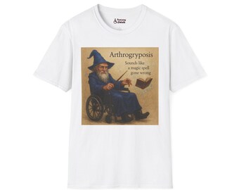 May include: White t-shirt featuring a humorous graphic. The graphic depicts a wizard in a wheelchair, with the text "Arthrogryposis Sounds like a magic spell gone wrong."