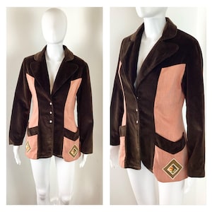 May include: A brown velvet blazer with a pink corduroy panel and brown embroidered details. The blazer has a notched collar, long sleeves, and a single-breasted closure with buttons.