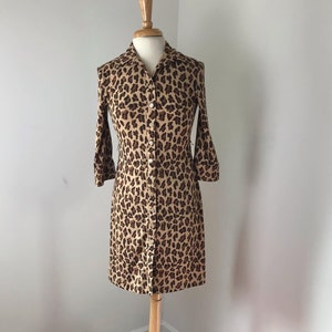 May include: A brown and black leopard print button-down dress with long sleeves.