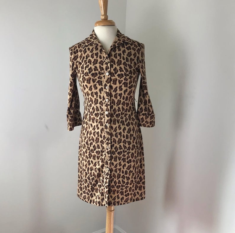 May include: A brown and black leopard print button-down dress with long sleeves.