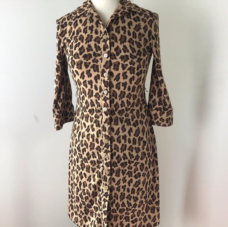 May include: A brown and tan leopard print button-down shirt dress with long sleeves.