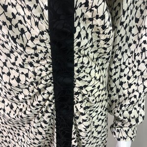 May include: A white and black patterned long-sleeved dress with a black velvet trim down the front.